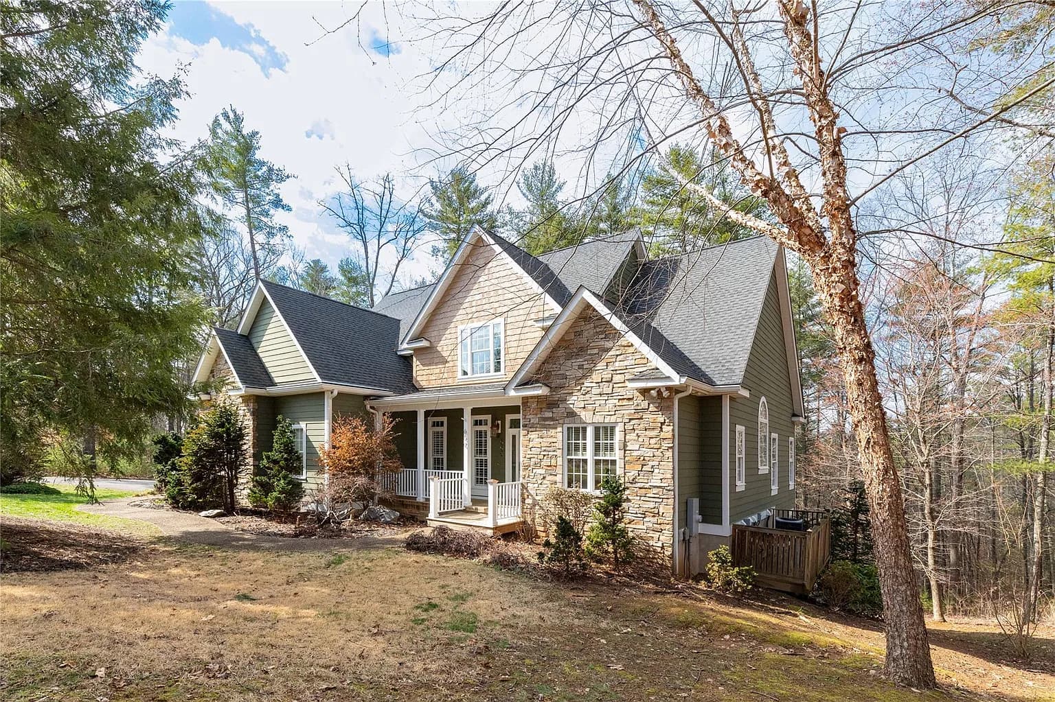 Custom home with stone facade surrounded by mature trees